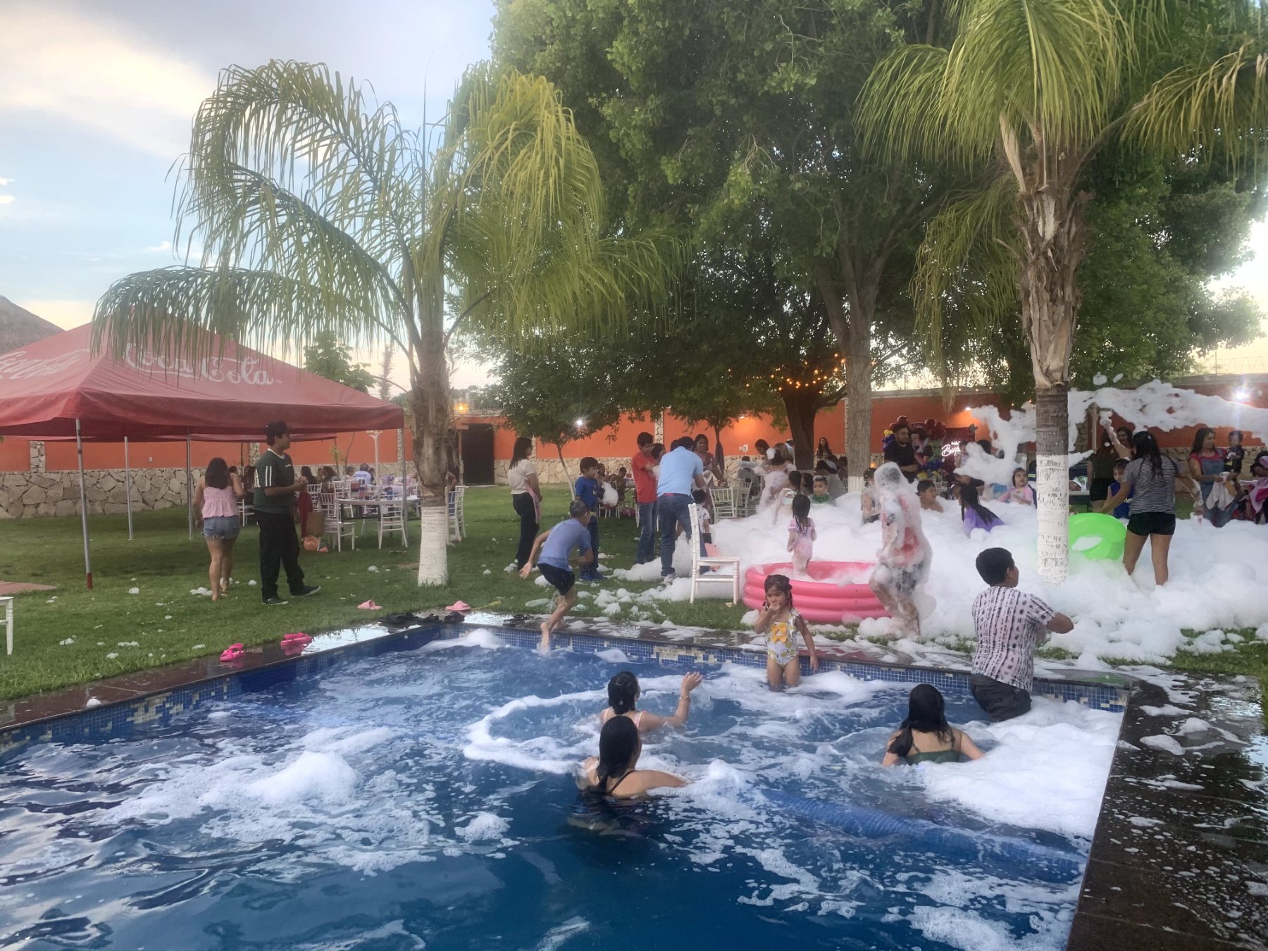 Niños divirtiéndose en la alberca con jabón y espuma, rodeados de árboles y un jardín hermoso en Quinta Paris, Lerdo.